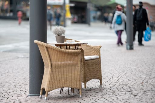 A selective focus shot of chairs with decorative flower on a small table placed outside with a blurred background