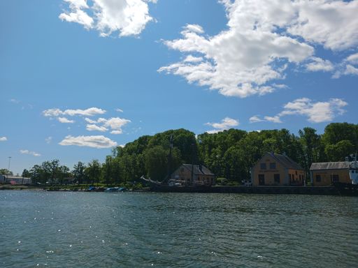 An idyllic small island located near a tranquil lake with several picturesque boats in the foreground