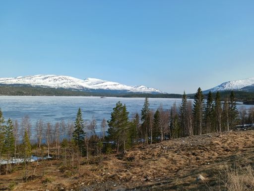 A scenic view of a tranquil lake in the foreground, with snow-capped mountains in the background