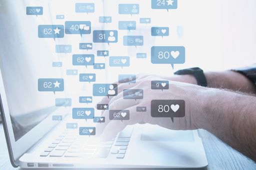 Hands typing on a laptop with social media icons - the concept of networking
