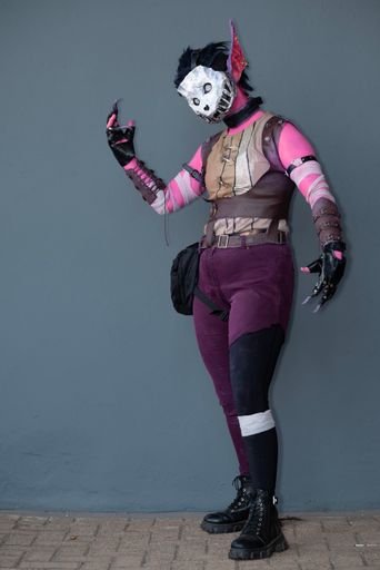 A female cosplayer dressed as a pink monster with a skull mask