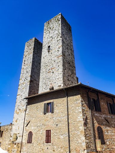 A vertical shot of Piazza del Duomo in San Gimignano, Italy under a blue sky