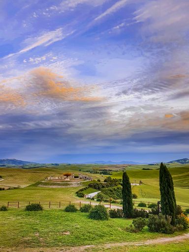 A vertical shot of unpaved road along a green field in Peccioli, Tuscany under a dramatic sky