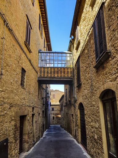 A vertical shot of an old alleyway along stone buildings in Peccioli, Tuscany
