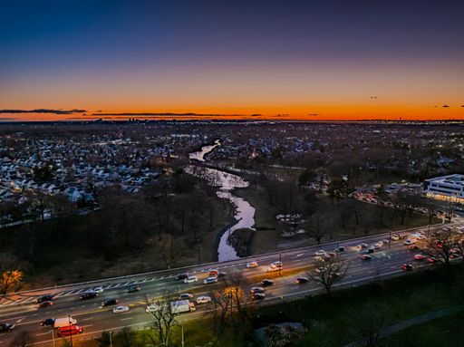 An aerial view of a highway and Long Island Railroad tracks at sunset in New York, United States