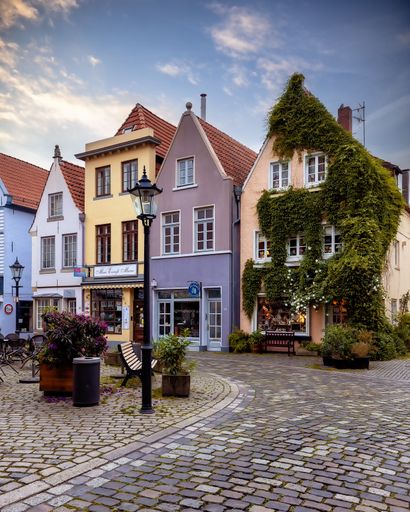 A picturesque cobblestone street in a quaint town lined with brightly colored traditional buildings.