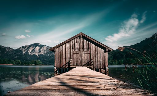 A picturesque wooden fishing shack situated on a dock overlooking a serene lake in Chiemsee, Germany
