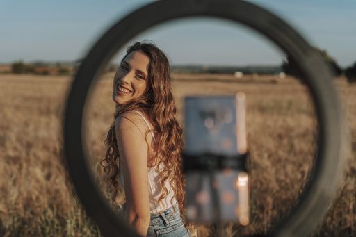 A gorgeous Spanish woman smiling at her phone while taking a selfie with it attached to a ring light