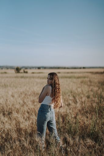 A beautiful Spanish girl looking over her shoulder with curly blond hair in a sunny wheat field