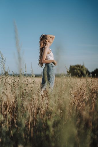 A beautiful Spanish girl holding her hair tightly with closed eyes under the sun in a wheat field