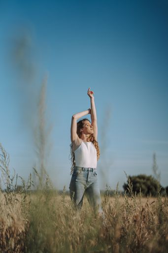 A vertical shot of a happy Spanish woman enjoying herself under the heat of the sun in a wheat