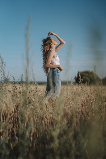 A vertical shot of a beautiful Spanish girl playing with her blond hair in a wheat field