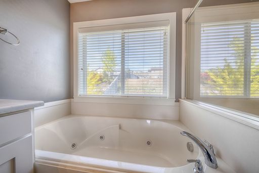 A closeup shot of a jacuzzi bathtub in a bathroom with big window and mirror