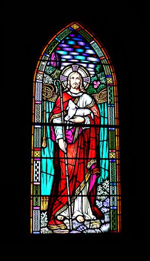 A vertical shot of a Good Shepherd stained glass, church window of Jesus Christ isolated on black background