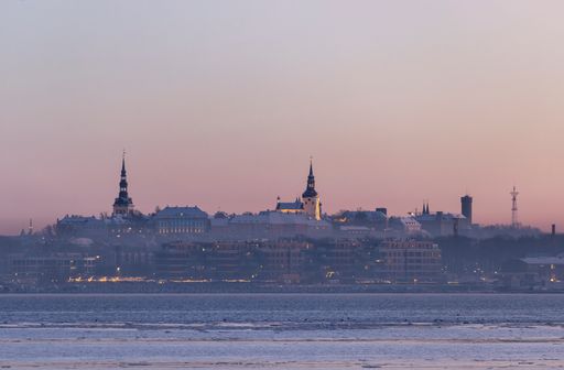 A scenic view of the skyline of Tallinn city skyline over the sea bay at sunset