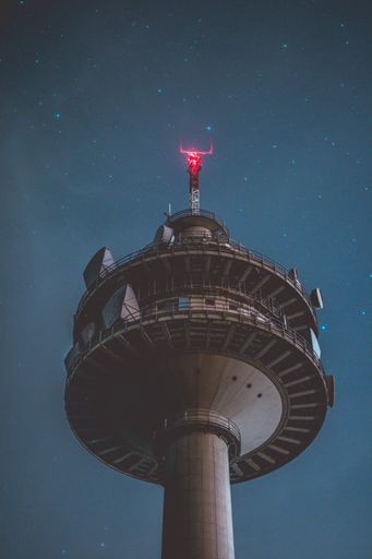 A vertical low angle shot of a grey tall tower at night with beautiful stars in the background