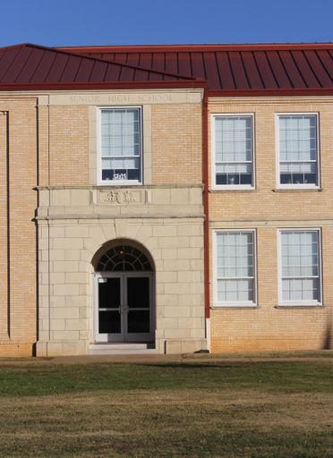 The facade of an Old School Building in New London, TX on a sunny day