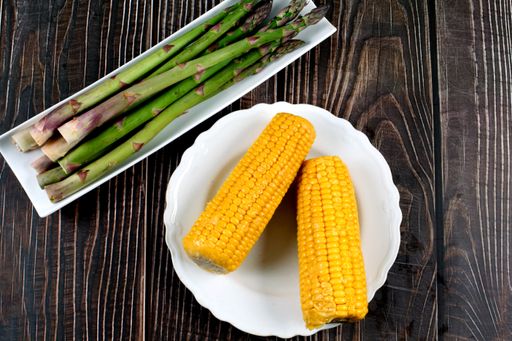 A top view of fresh corn and asparagus on a wooden table