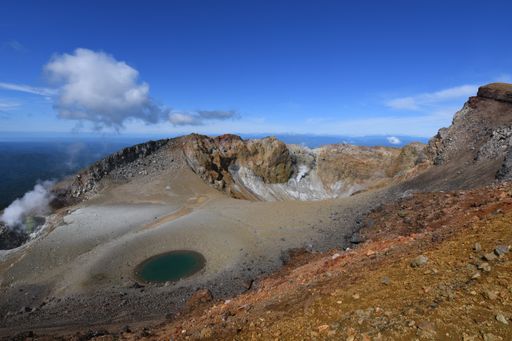This aerial view showcases a captivating landscape featuring a series of small lakes surrounded by mountains and the edge of a volcano