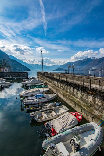 A vertical shot of parked boats and mountains in the background under a cloudy sky