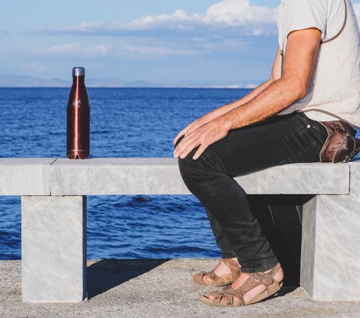 A closeup shot of a traveller sitting on a bench near a sea