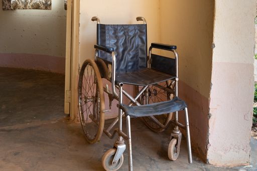 An old, rusty wheelchair is in the hallway of a hospital in Uganda
