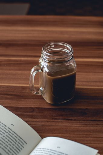 A closeup vertical shot of a glass cup of hot chocolate on a wooden table