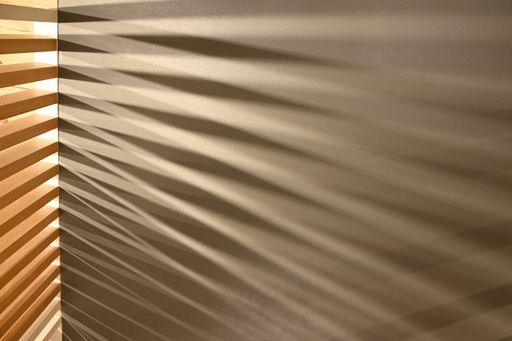 A closeup shot of ray lights through wooden pattern frame creating graphic shadows on gray surface