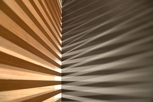 A closeup shot of ray lights through wooden frame creating graphic shadows on gray surface