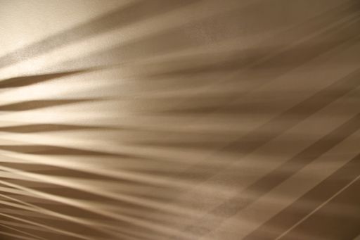 A closeup shot of ray lights through wooden frame creating graphic shadows on gray surface