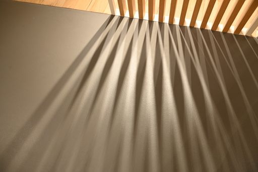 A closeup shot of ray lights through wooden frame creating graphic shadows on gray surface