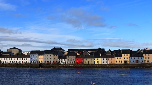 A vibrant array of houses in various bold colors, dotting the shoreline in Galway Ireland.