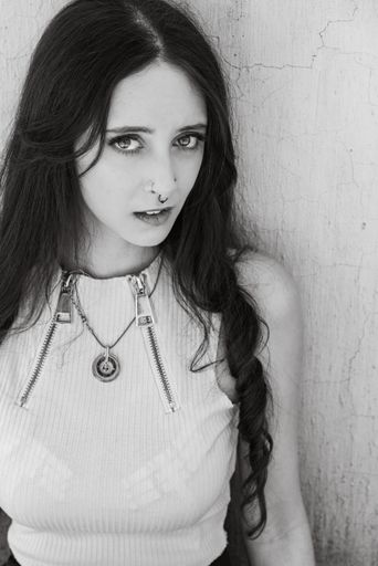 A grayscale shot of a goth girl in an urban setting