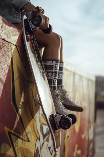 A vertical shot showing a skateboard next to a girl's legs