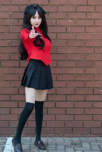A female cosplayer with black hair in a black skirt and red shirt with a cross on it