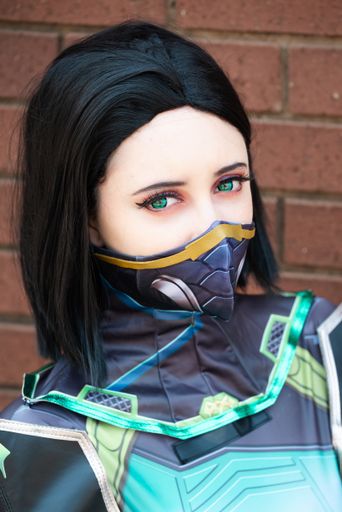 A closeup portrait of a female cosplayer in a green action suit