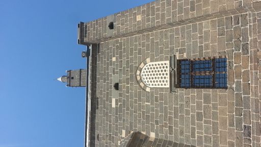 A low angle shot of the facade of a historical brick building against aclear blue sky