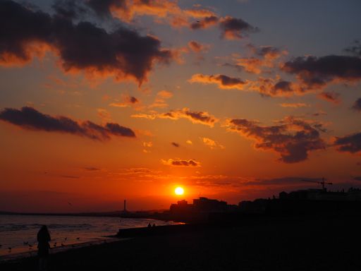 A landscape of buildings surrounded by the sea during a beautiful red sunset in the evening