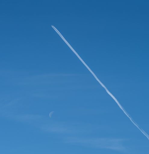 An airplane soaring through the clear blue sky, leaving behind long white contrails in their wake