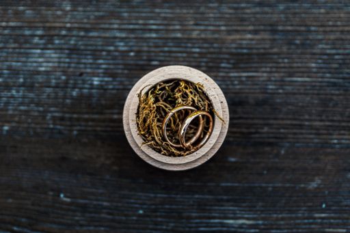 A high angle view of two golden rings in a round box on the table under the lights