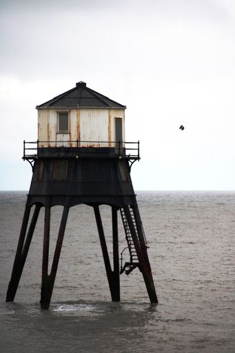 A vertical shot of an aged lighthouse in the middle of a sea