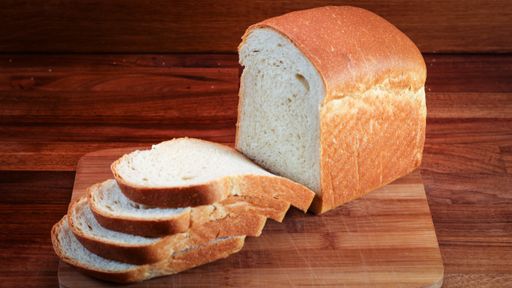 A closeup of a cutting board with sliced toast bread on it in a bright kitchen