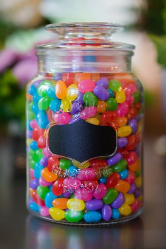 A vertical shot of a glass jar filled with colorful jelly beans