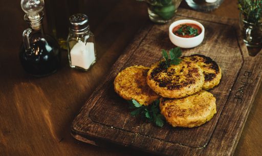 A high angle shot of vegan cutlets on a wooden tray served with sauce and seasonings