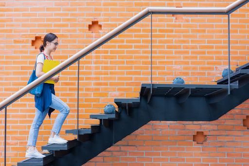 A young university student walking up the stairs in a university campus