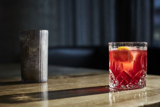 A closeup shot of a glass of cocktail on a wooden table with a blurred background