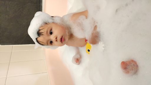 A vertical shot of a cute toddler taking a bath