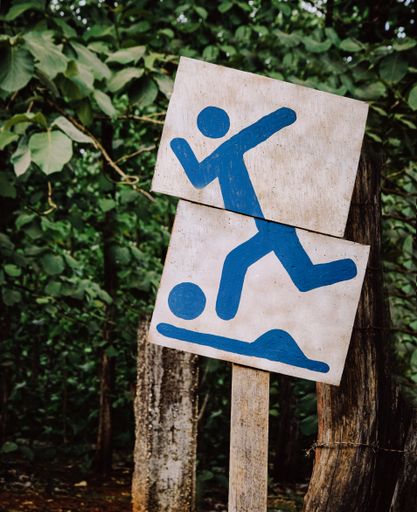 A vertical shot of a blue painted signboard of a man playing football