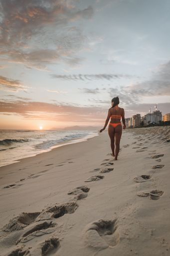 A sexy young female walking on the white sand beach at sunset