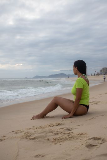 A young female sitting at a white sand beach and enjoying the view of the stormy sea